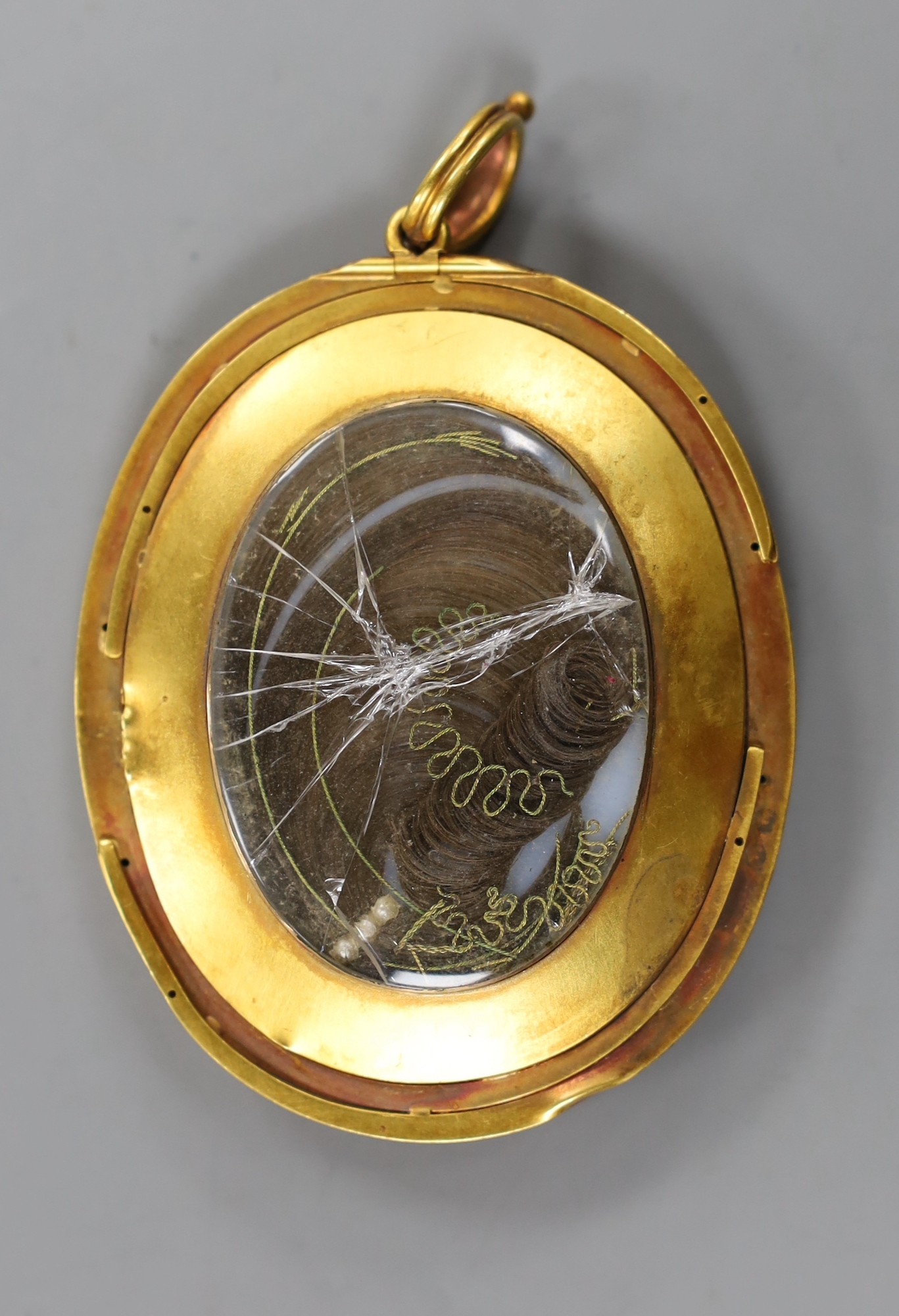 A yellow metal mounted oval portrait miniature of a young lady pendant miniature, the glazed back with plated hair beneath, 67mm, gross weight 42.7 grams.